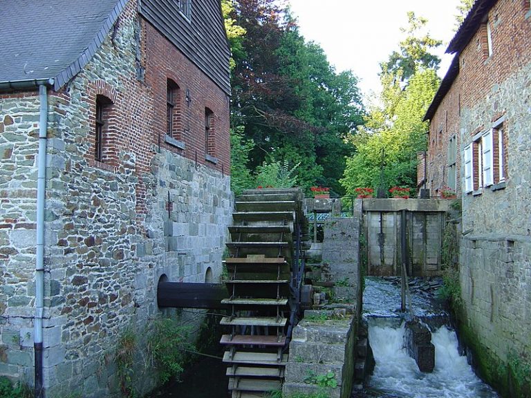 Exterior grounds of a monastery, displaying a large waterwheel