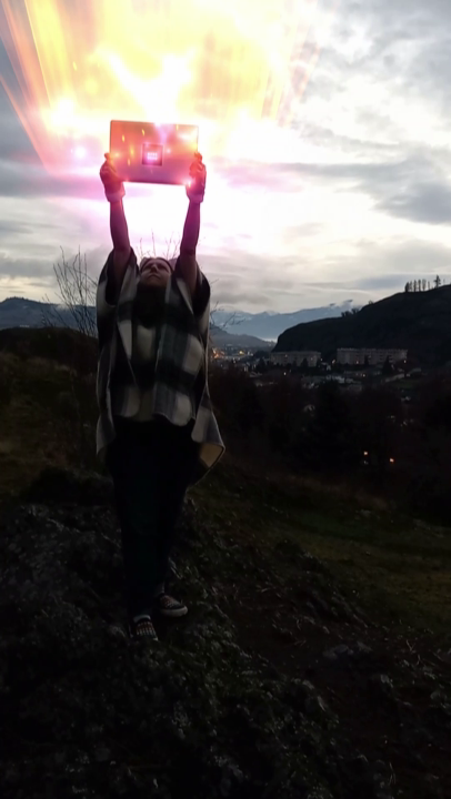 A woman in bunny ears raises a magically-glowing laptop to the sky triumphantly