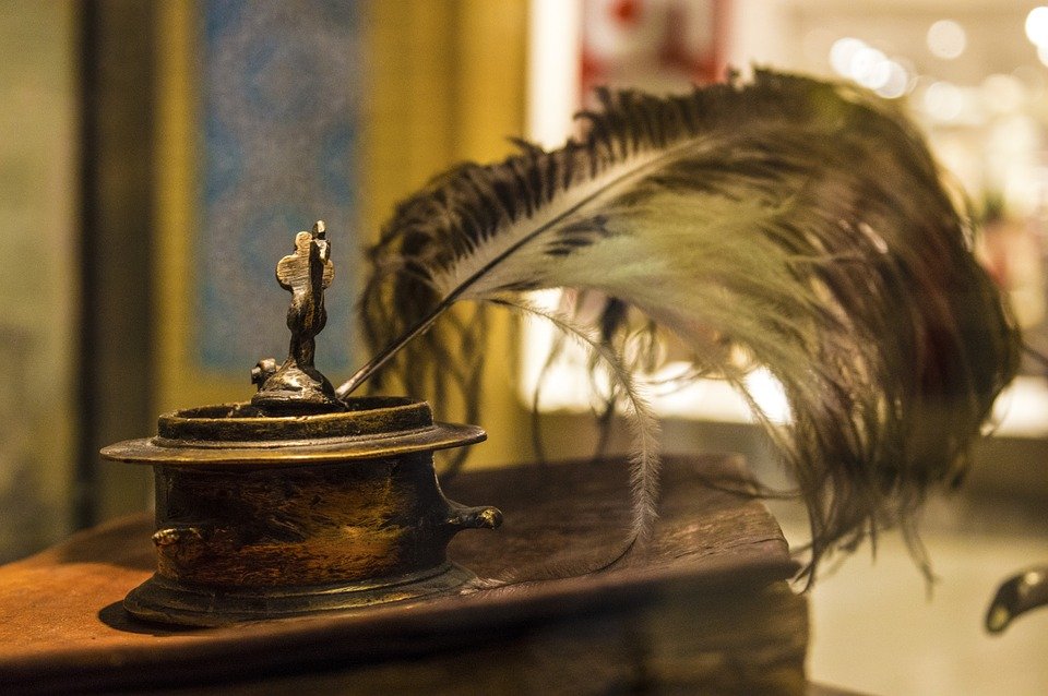 An old fashioned ostrich feather quill and inkwell on a corner table