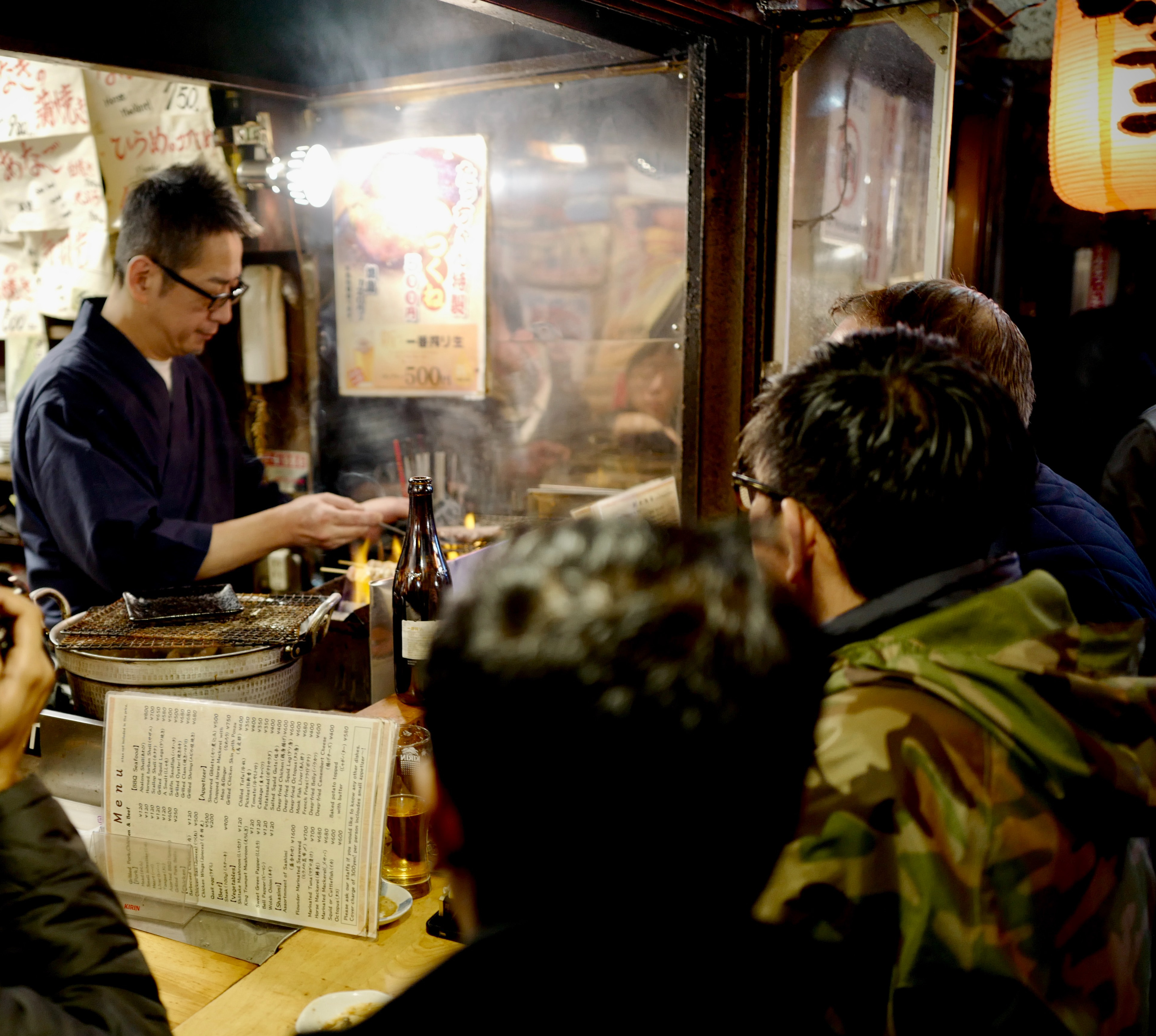 Japanese pub where a cook is gilling meat