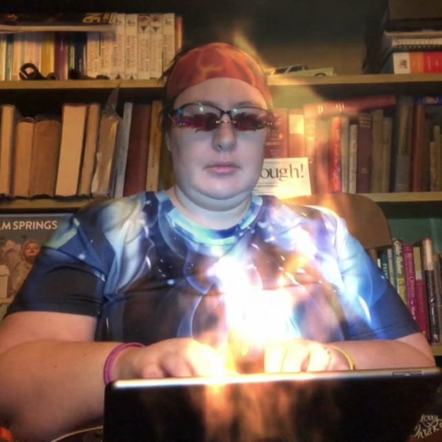 A writer typing at a laptop that is producing magical fire