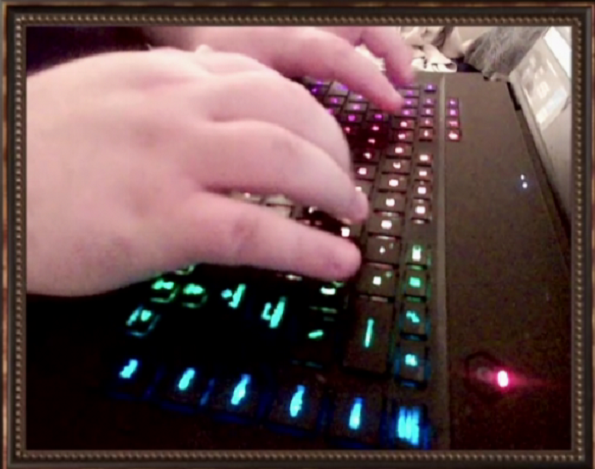 A man's hands typing on a rainbow-illuminated keyboard