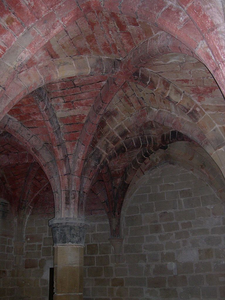 Interior of an early Gothic monastery, showing pink stone and a vaulted ceiling